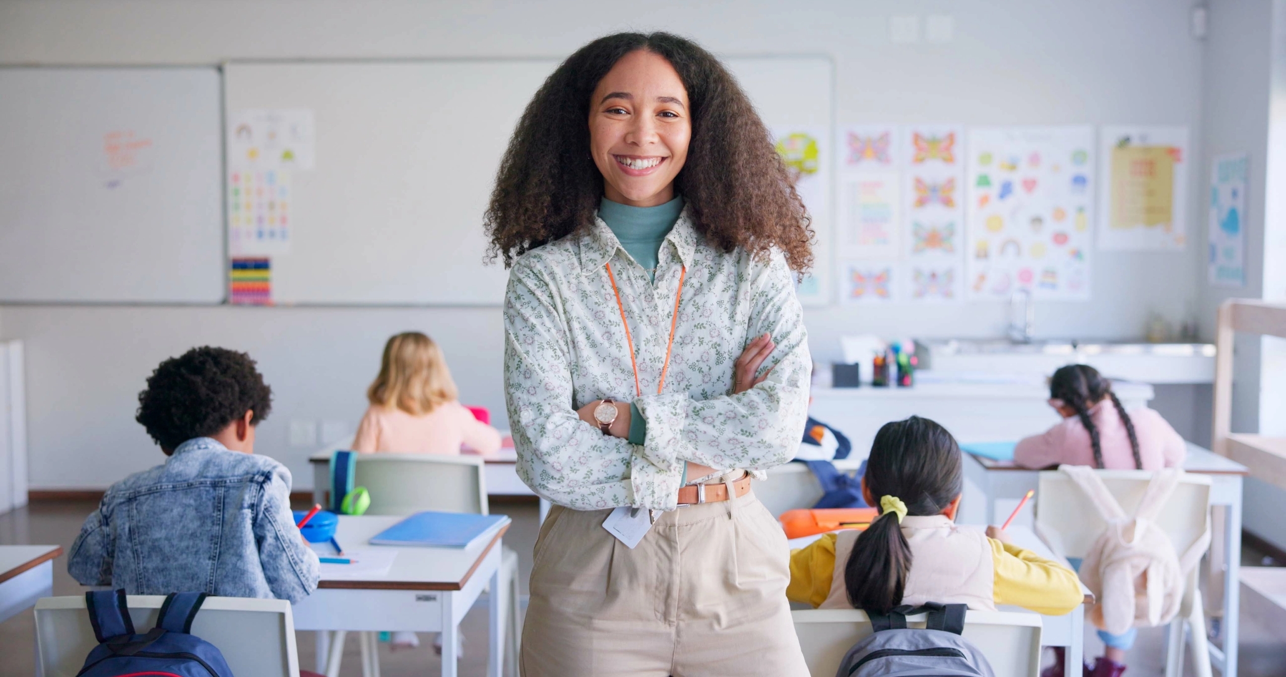 eine Lehrerin schaut in die Kamera die Kinder sind im Hintergrund zusehen